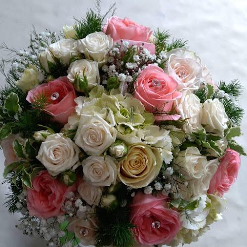 Un bouquet composto da un mix di rose rosa, bianche e crema con fogliame verde e rametti di gypsophila bianca.