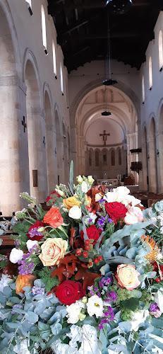 All'interno di una chiesa è collocata una grande composizione floreale, con banchi e finestre ad arco sullo sfondo.