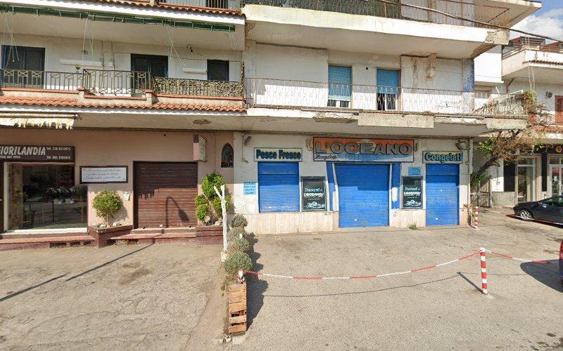 Vista a livello stradale di un edificio con vetrine chiuse, tra cui un negozio chiamato "IL DOLCIANO" con persiane blu. Adiacente c'è un altro negozio chiuso chiamato "TORTALANDIA". Un'auto parcheggiata è visibile sulla destra.