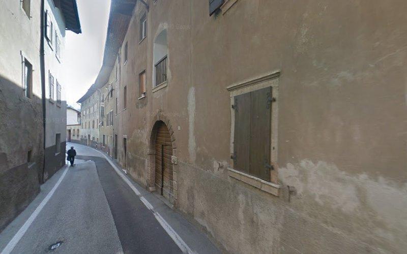Una stretta strada acciottolata fiancheggiata da edifici antichi. Una persona si allontana in lontananza sul lato sinistro della strada.