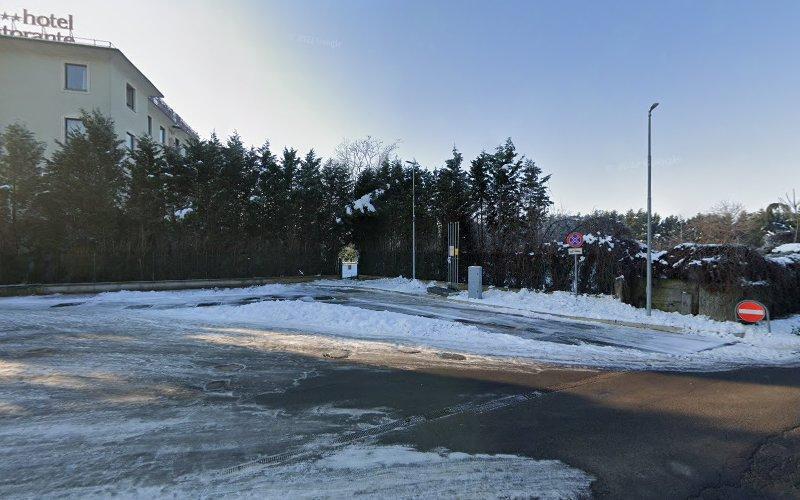 Un angolo di strada innevato con un cartello "non entrare" e un edificio a più piani sulla sinistra. Alberi fitti e innevati costeggiano lo sfondo. La zona sembra tranquilla e deserta.