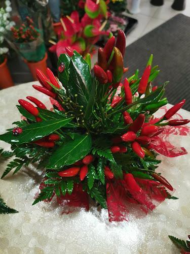 Un piccolo bouquet di verde e peperoncini rossi disposti con alcuni nastri decorativi rossi.