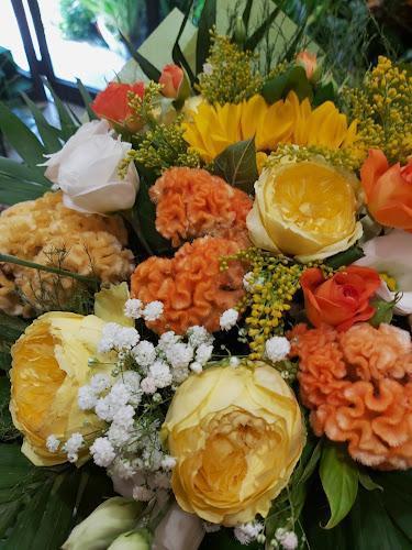 Un bouquet colorato con rose gialle, gypsophila, girasoli e fiori arancioni e bianchi con fogliame verde.