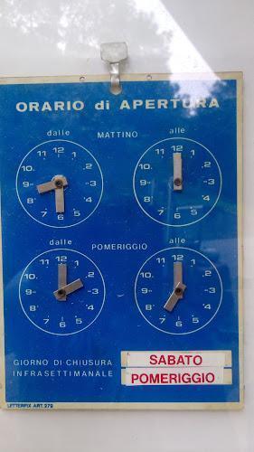 Un cartello blu indica gli orari di apertura al mattino (8:00 - 12:00) e al pomeriggio (15:00 - 19:00). Chiuso il sabato pomeriggio.