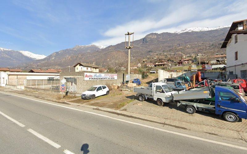 Veduta aerea di un'officina di riparazione auto con diversi veicoli parcheggiati e una catena montuosa sullo sfondo.