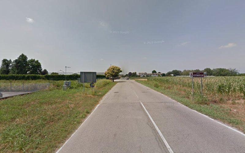 Una strada di campagna fiancheggiata da campi, un cartello stradale con la scritta "Cittadella" sulla destra, alberi sullo sfondo e un cielo parzialmente nuvoloso in alto.