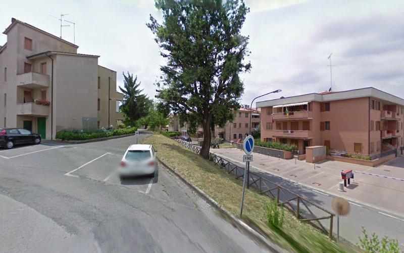 Una strada residenziale in pendenza e tranquilla con auto parcheggiate e alberi, fiancheggiata da edifici a più piani. Un cartello di traffico a senso unico è visibile in primo piano.